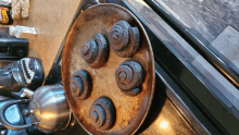 a bunch of cinnamon rolls are on a pan on a stove top with a bottle of doughnuts in the background