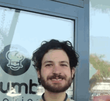 a man with a beard is smiling in front of a sign that says ' gumbo ' on it