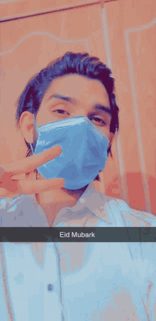 a man wearing a blue face mask with the words eid mubarak written below him