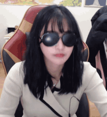 a woman wearing sunglasses and headphones sitting in a chair