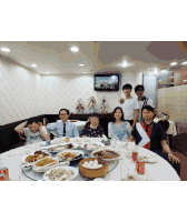 a group of people posing for a picture in front of a table full of food including one wearing a shirt that says next