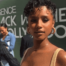 a woman with curly hair stands in front of a sign that says essence
