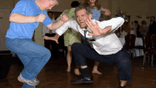 a group of people are dancing on a dance floor and one man is squatting down