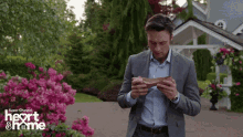 a man in a suit is holding a piece of paper in front of a house with the words heart & frame on the bottom