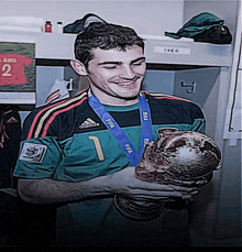 a soccer player wearing a green adidas jersey holds a trophy