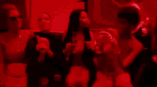 a group of people are dancing in a room with red light .