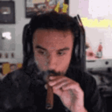 a man wearing headphones is smoking a cigar in front of a computer screen .