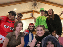 a group of people are posing for a picture and one of them is wearing a red m & m costume