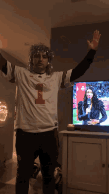 a man in a number 1 jersey stands in front of a tv