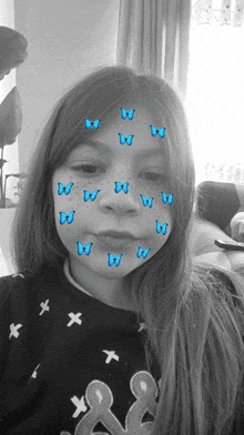 a girl with blue butterflies on her face has the letter w on her shirt