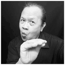 a man in a black shirt is blowing a kiss with his hand