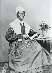 a woman sits at a table with a vase of flowers in front of her