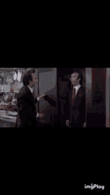 two men in suits and ties are standing next to each other in a dark room with the words imgplay at the bottom of the screen