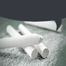 three white chalk sticks laying on a chalkboard with a speech bubble in the background