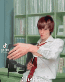 a man in a white shirt and red tie is standing in front of a bookshelf with the word chadachi on the bottom