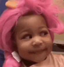 a little girl is wearing a pink wig and curlers on her head .