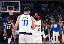 two basketball players wearing dallas jerseys are talking to each other