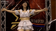 a woman in a crop top and shorts is dancing in front of a sign that says five star gp 2024