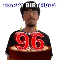 a man with glasses is holding a cake with candles in the shape of the number 96
