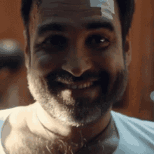 a man with a bandage on his forehead is smiling for the camera