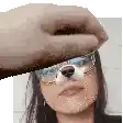 a hand is holding a picture of a woman wearing glasses and a dog nose .
