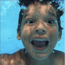 a young boy is swimming underwater with his mouth wide open