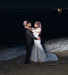 a bride and groom pose for a picture on the beach