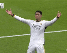 a soccer player wearing an emirates fly better jersey stands on the field