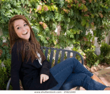 a woman is sitting on a bench with her legs crossed and laughing .