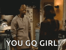 a man is standing in a kitchen talking to a woman and saying `` you go girl '' .