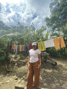 a woman in a white shirt stands in front of a clothes line