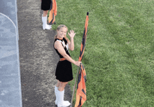 a cheerleader is holding an orange and black flag and waving