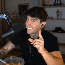 a man with a ring on his finger is smiling in front of a microphone and a bowl of cereal