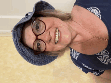 a woman wearing glasses and a blue hat is smiling