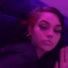 a woman is laying on a bed with purple lights behind her and making a funny face .