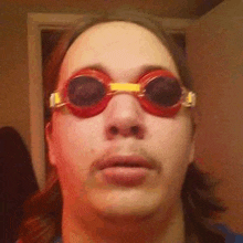 a man wearing a pair of red swimming goggles is looking at the camera .