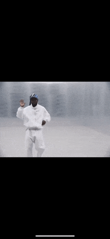 a man in a white jacket and pants is dancing in a white room .