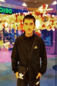 a young man wearing an adidas jacket stands in front of a store