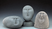 three rocks with faces carved into them are sitting next to each other on a table