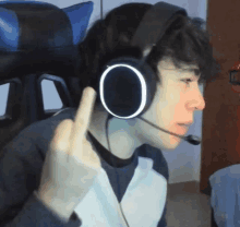 a young man wearing headphones and a microphone giving the middle finger