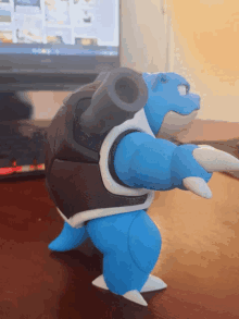 a toy turtle with a cannon on its back is on a table in front of a laptop