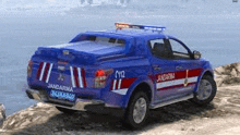 a blue jandarma truck is parked on the side of a road near the ocean .