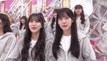 a group of girls are standing in front of a pink and silver background