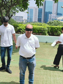 a man wearing a blindfold is walking on a lush green field