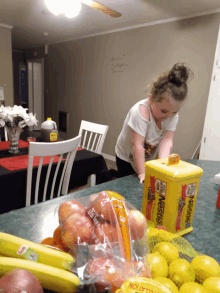 a little girl reaches for a nestle box on a counter