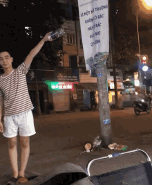 a man holds up a bottle of water in front of a sign that says " vi mot ni truong "