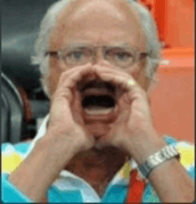 an older man with glasses is covering his mouth with his hands .