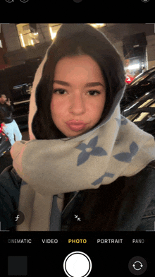 a woman wearing a scarf and a hoodie is taking a selfie