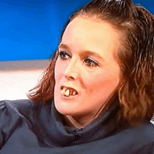 a close up of a woman 's face shows her teeth