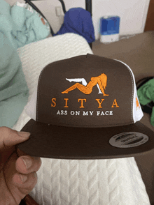 a person is holding a hat that says sity ass on my face